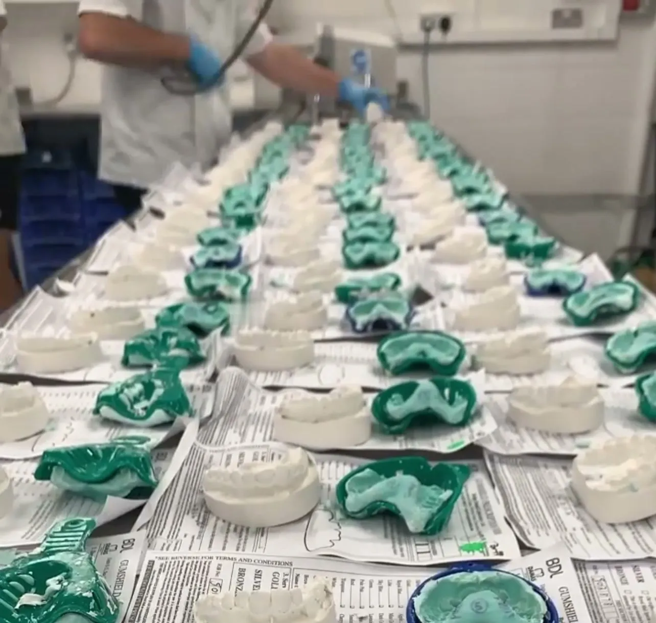 Rows of custom gumshields on dental models being finished by hand in the Bridge Dental lab